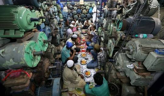 این عکس تعدادی از کارگران مسلمان هند را بر سر سفره افطار در یک فروشگاه پمپ آب در دهلی نشان می‌دهد.
