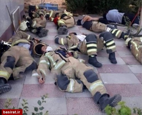آتش نشانانی که در عملیات اطفای حریق پالایشگاه تهران مشارکت داشتند و از فرط خستگی در حال استراحت در محل حادثه هستند