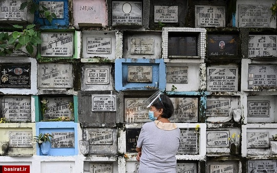 یک زن در مقابل قبر یکی از بستگانش در قبرستانی در مانیل- فیلیپین